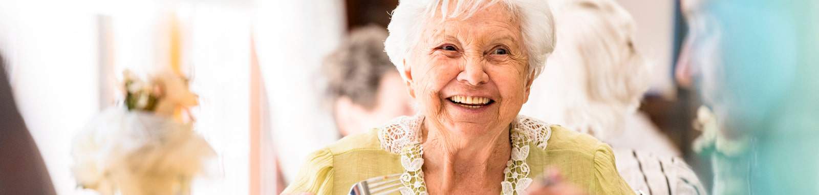 An older woman smiles and enjoys herself at a senior living community