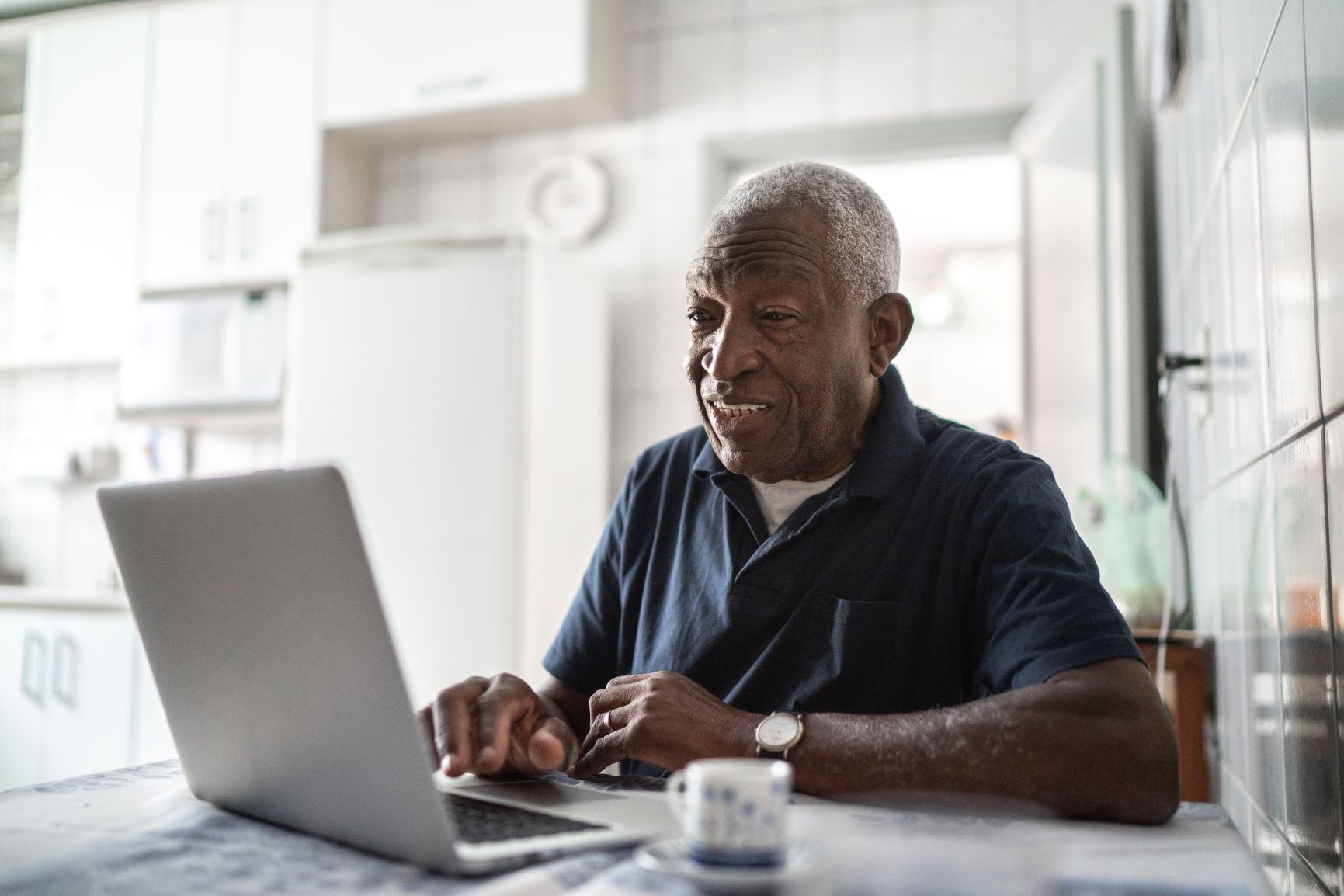 A senior man looks something up on his laptop