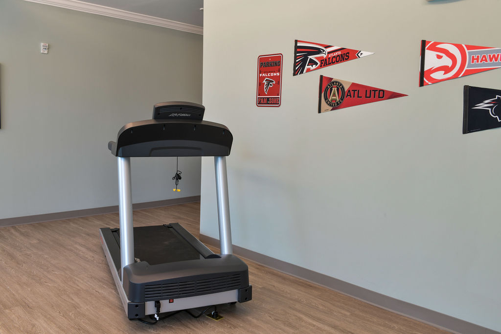 Treadmill in wellness room at True Light with sports decor on wall