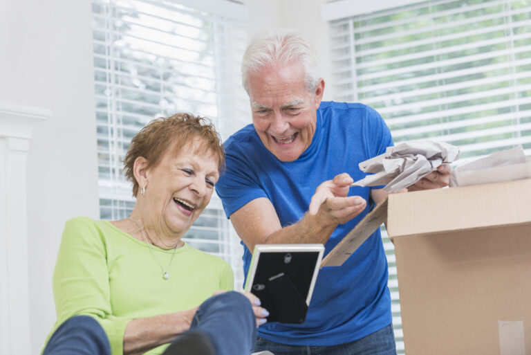 Senior couple laughing while packing—downsizing help for seniors