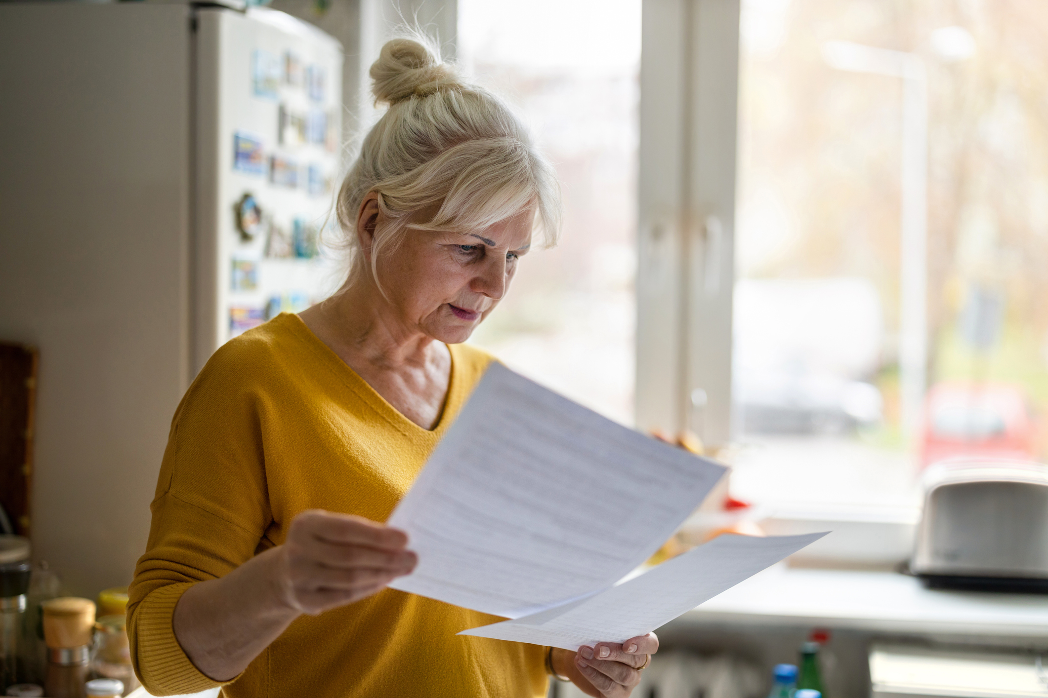 An older woman has finished writing a will and is reviewing it for common mistakes.