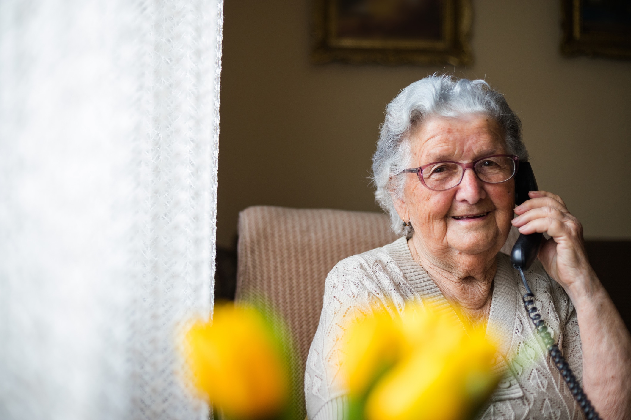 A senior woman talking with her long distance caregiver daughter over the phone.