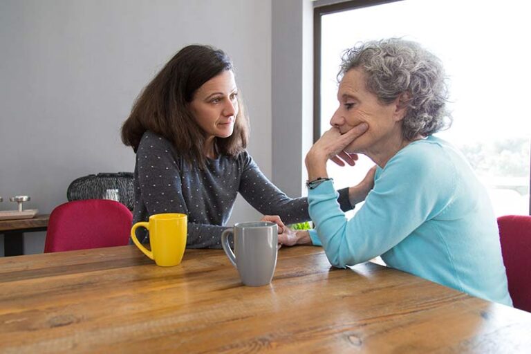 A senior woman contemplating while being comforted by another woman