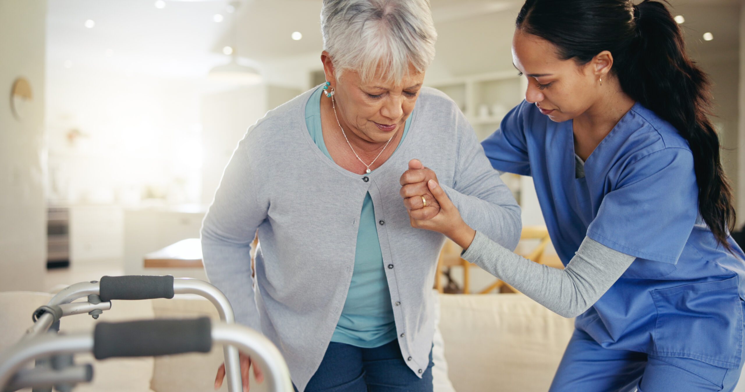 A nurse at a senior living community helping an older woman.