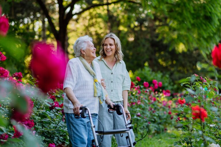 An adult granddaughter and her senior grandmother discuss levels of living for senior care during a walk in the park.