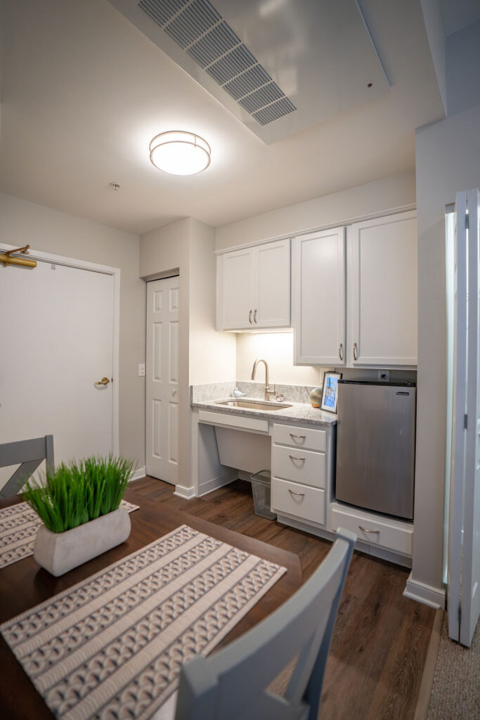 Small kitchenette with white cabinets and a mini-fridge