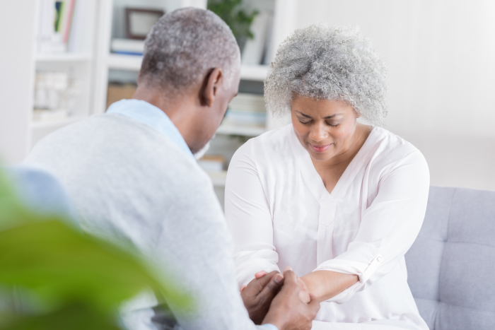 Senior woman sitting with a senior man holding hands
