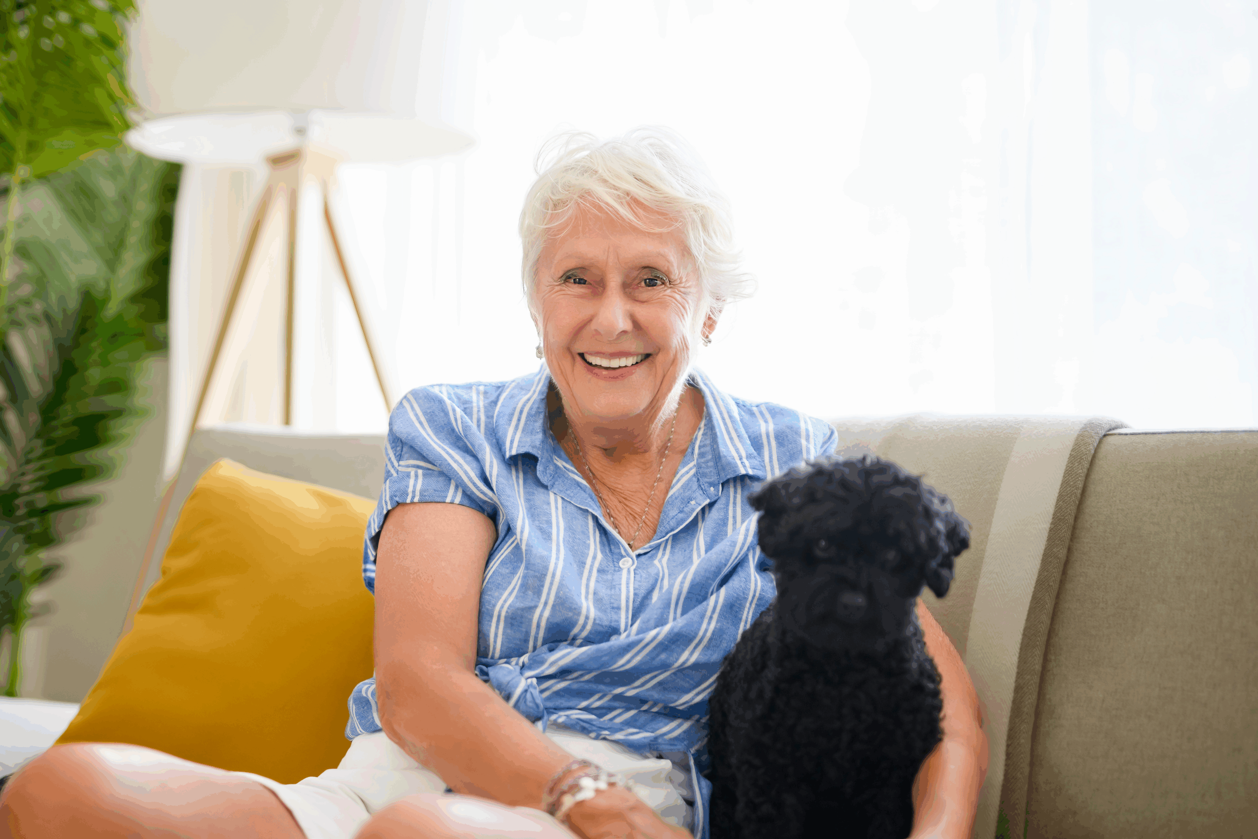 senior woman on a couch smiling with her dog