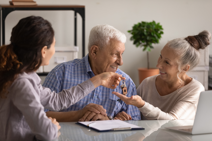 Two seniors sitting down receiving keys