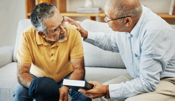 Man talking to another man while holding a book