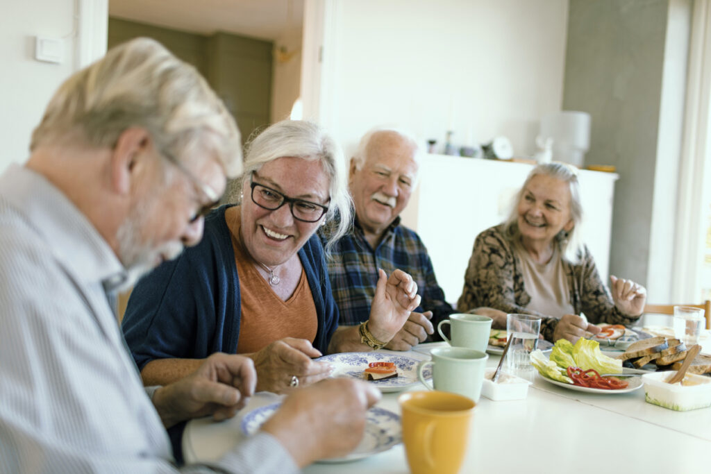 Four seniors laughing together at a dining table