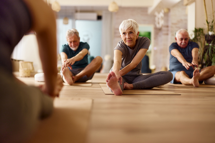 Seniors doing a seated forward fold stretch in a yoga class