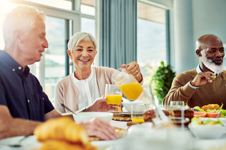 Senior pouring orange juice at breakfast_iStock-1167135985.jpg