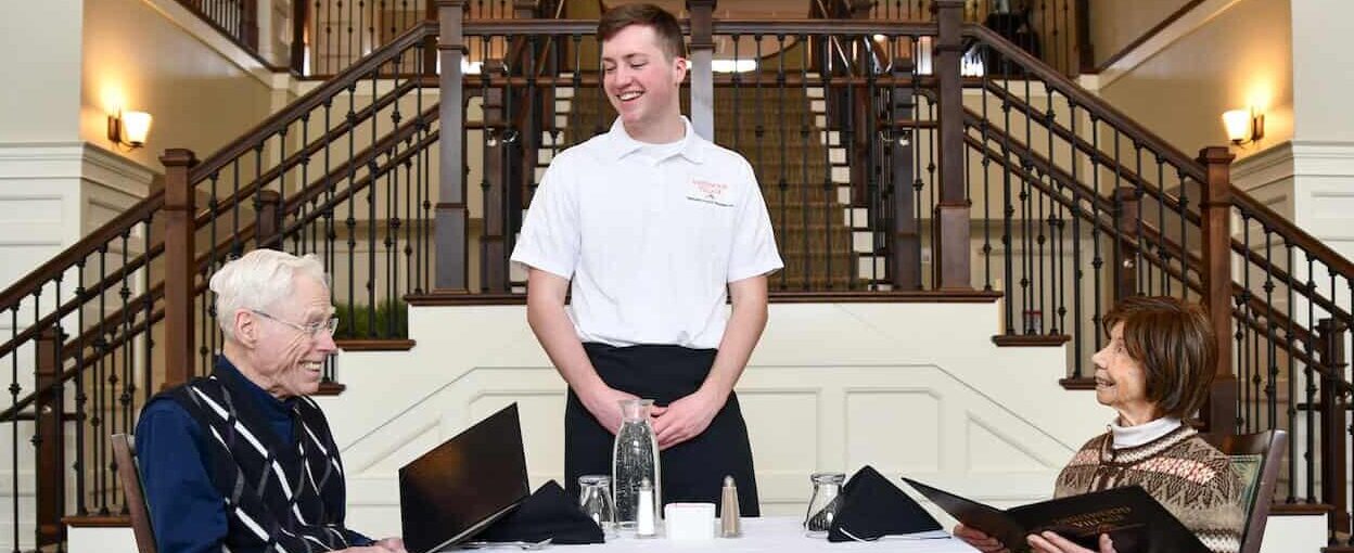 Server smiling at two seniors dining in a grand room