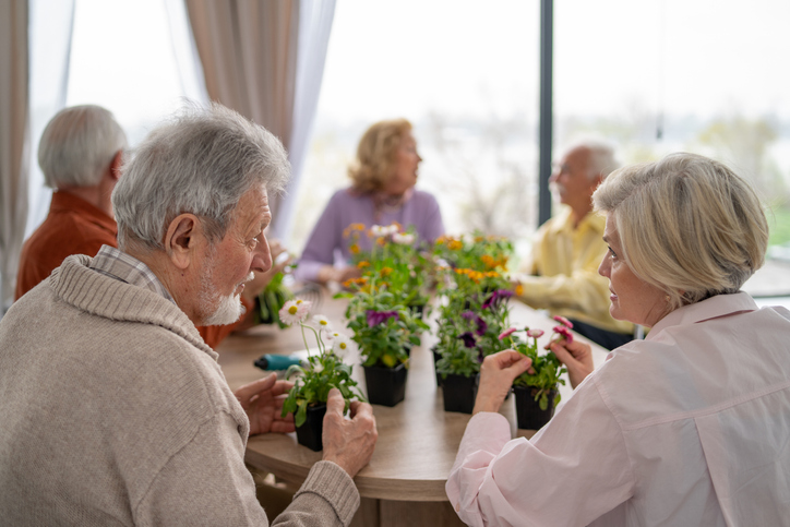 Group of seniors tending to potted plants at a table