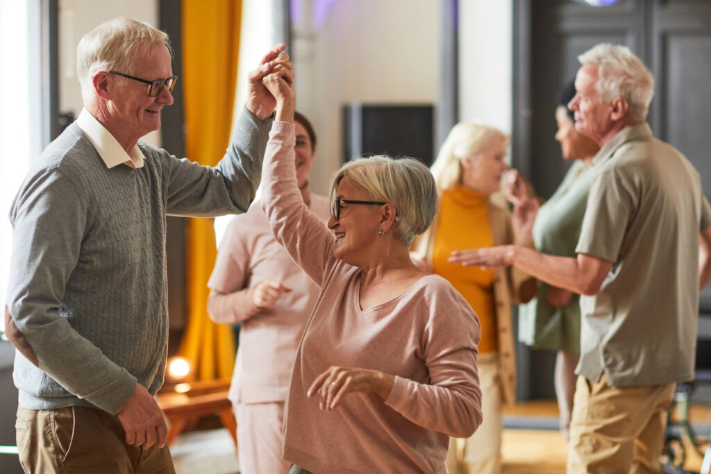 Happy senior couple dancing together in a bright room