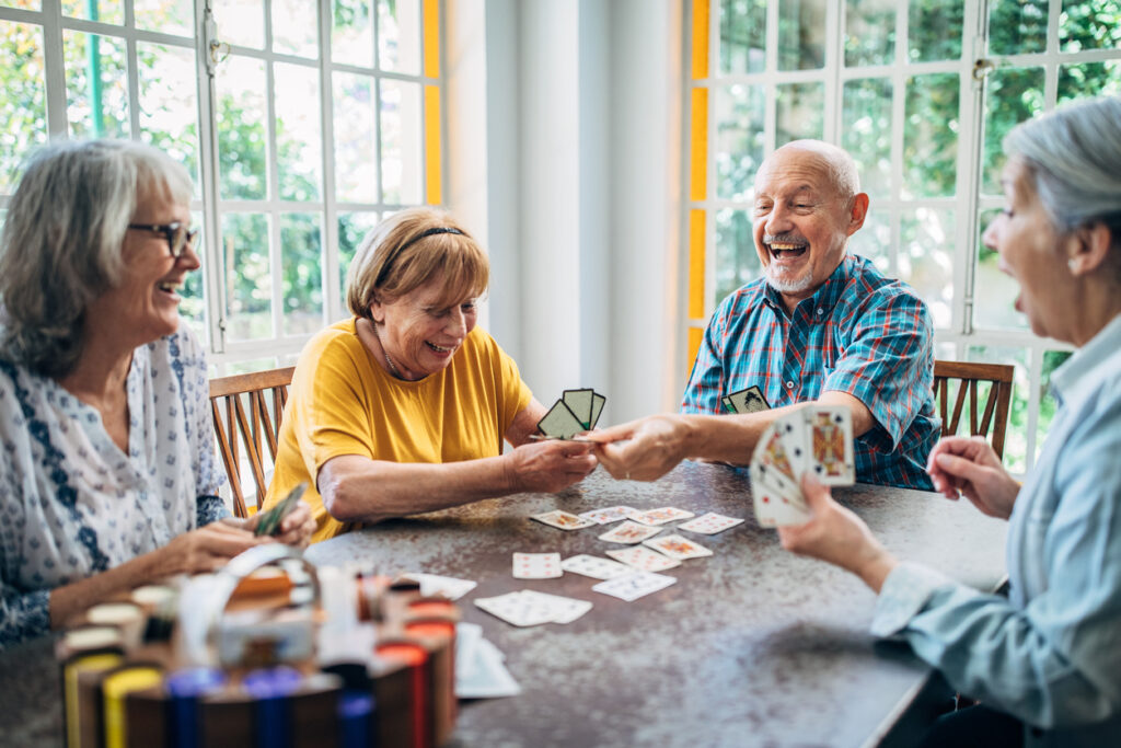 Four seniors playing cards and laughing at a table