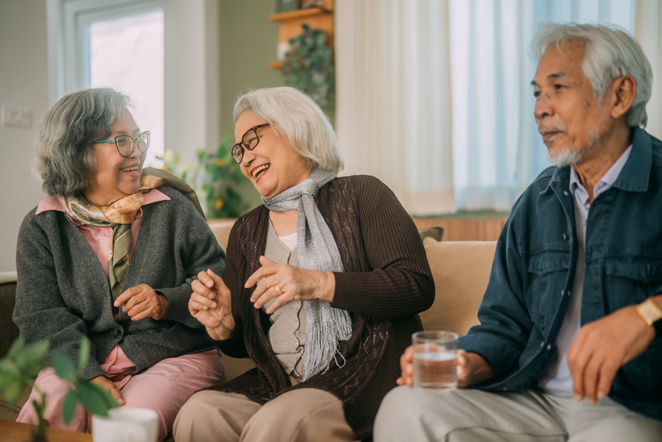 Three seniors laughing and talking on a couch