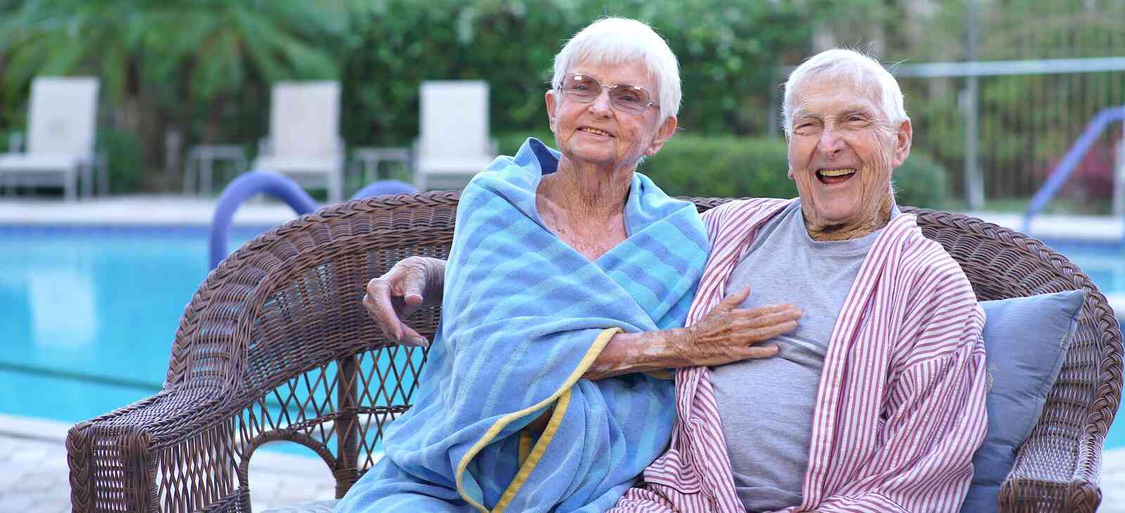 Happy seniors sitting by a pool after swimming