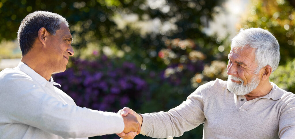 Two senior men shaking hands over a game