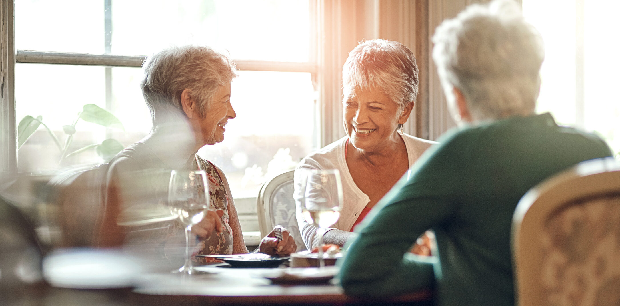 Smiling senior residents enjoying dinner at a communal table