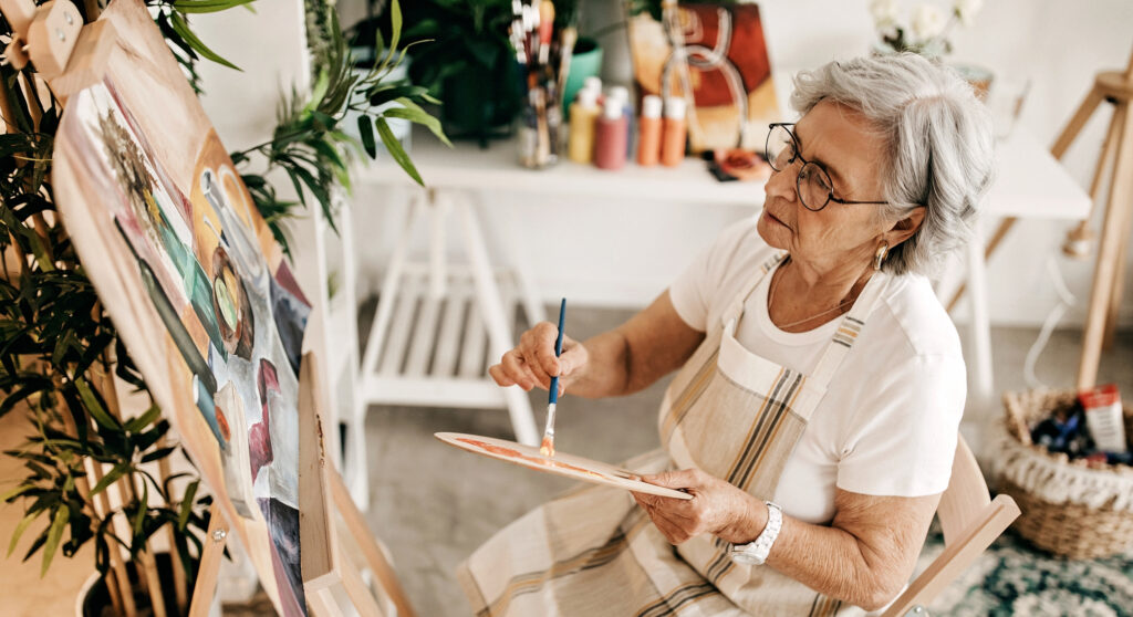 Senior women using acrylic colour to pain on canvas