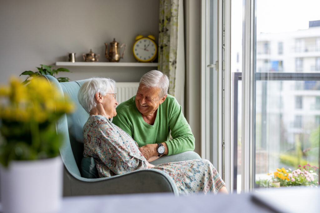 Senior couple smiling and talking in a bright, modern living room