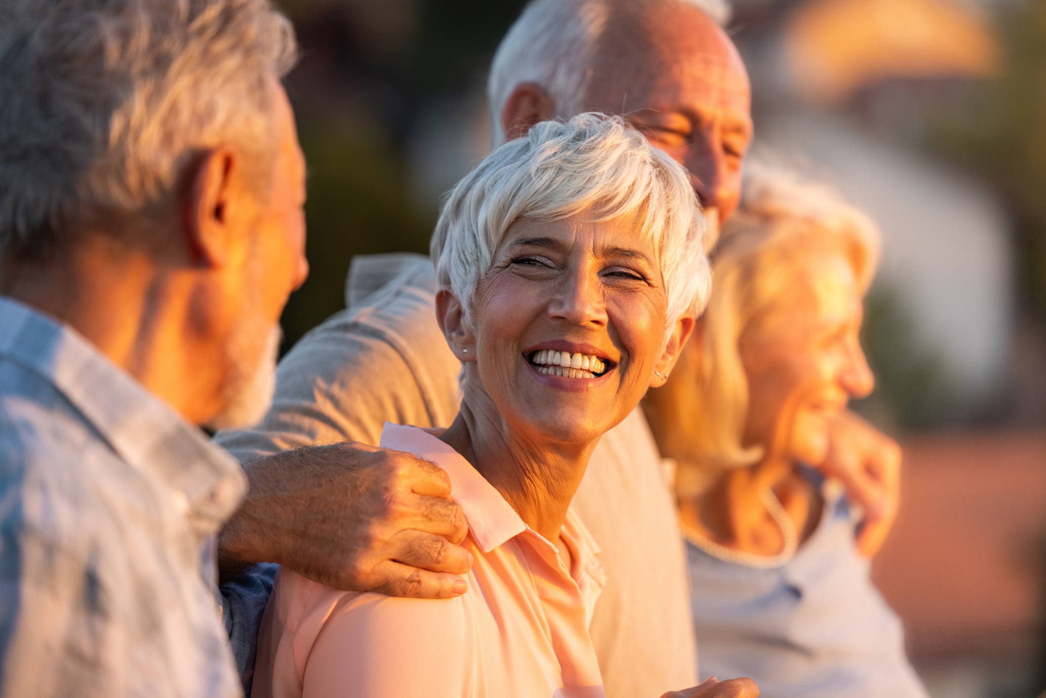 Happy senior woman smiling with friends at sunset