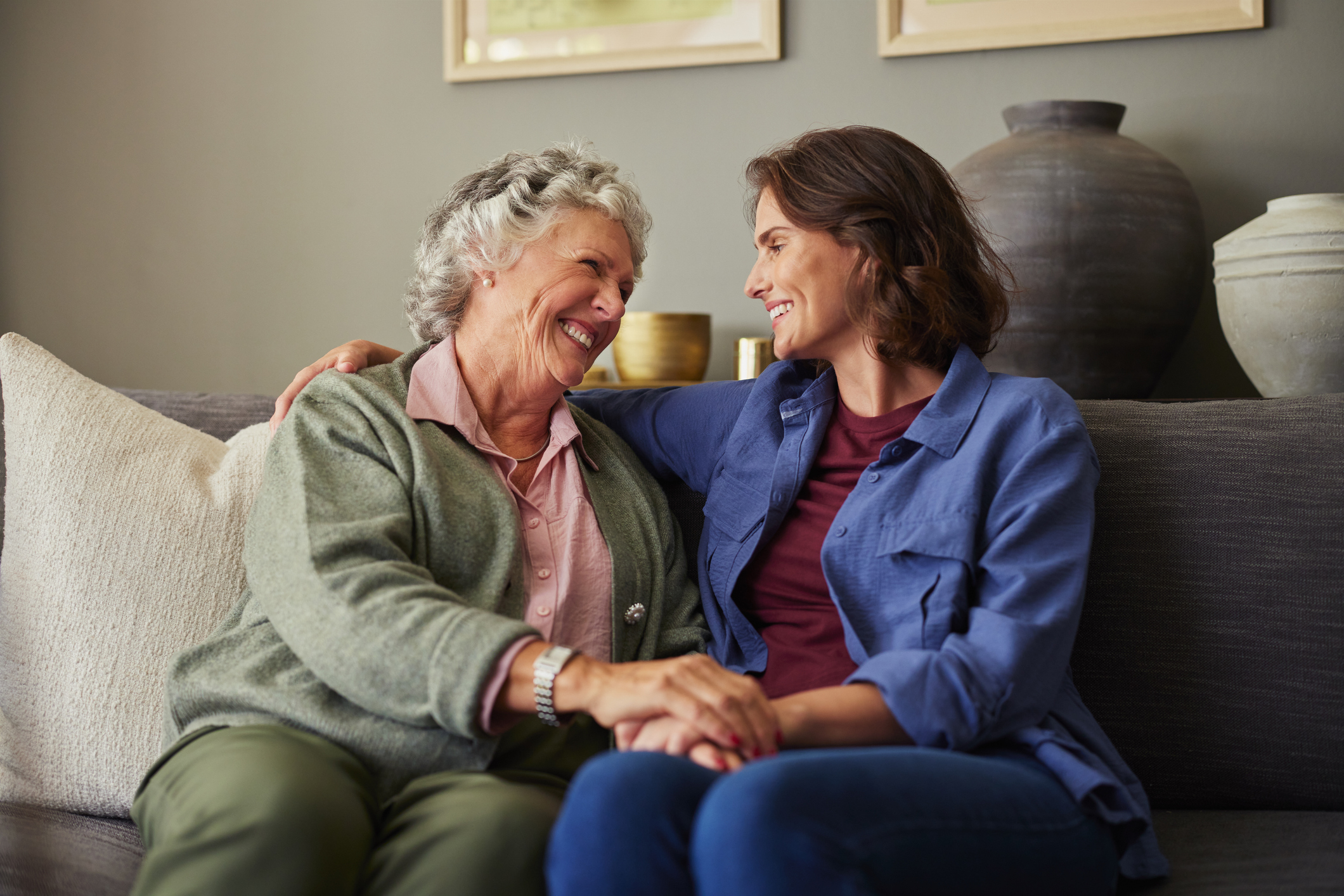 Senior woman and adult daughter smiling on a couch
