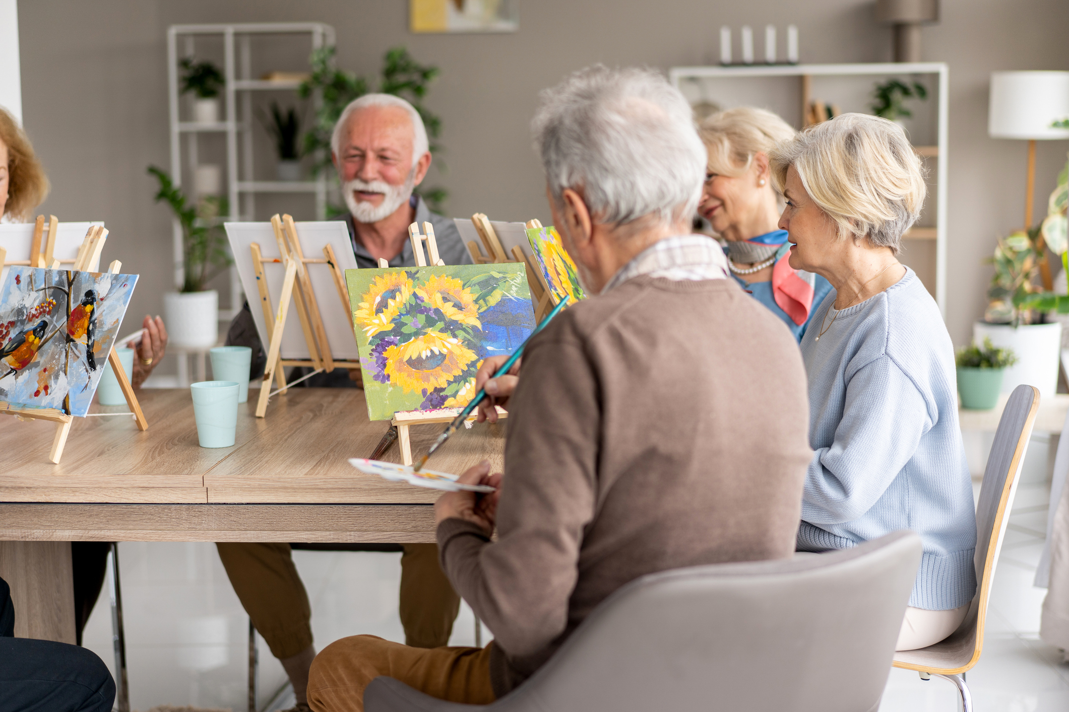 Group of seniors painting on easels in an art class