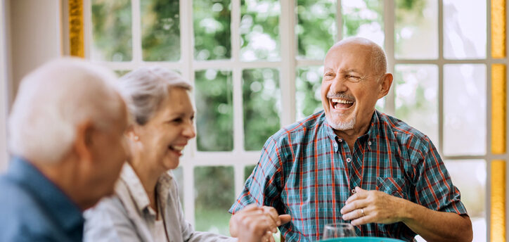 Seniors laughing together while sharing a meal