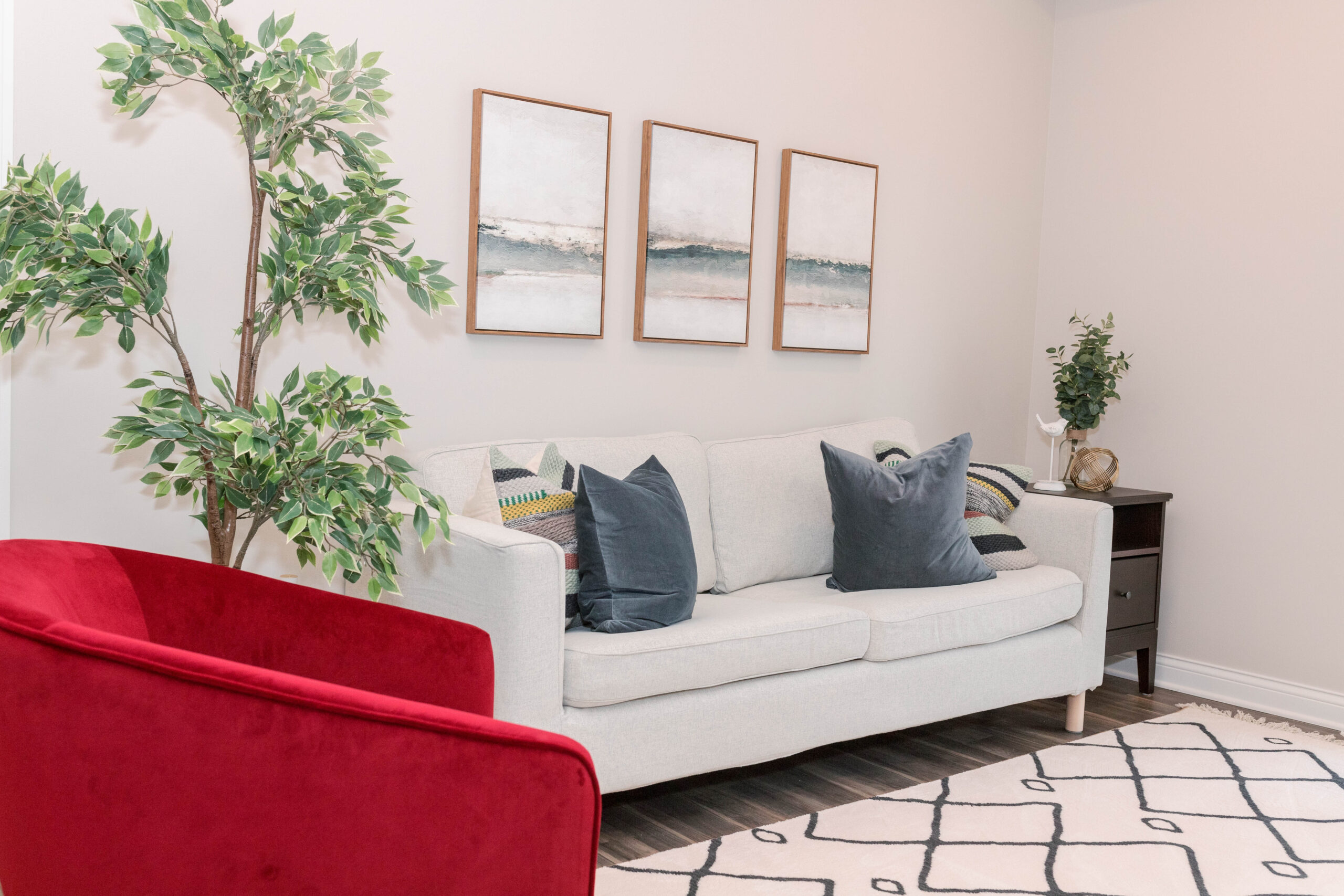 Modern living room with white sofa, red armchair, and abstract art