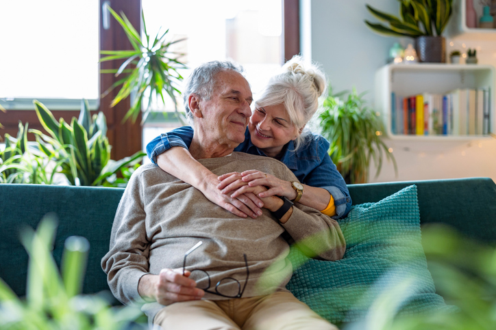 Happy senior couple embracing on a couch in a bright, modern room