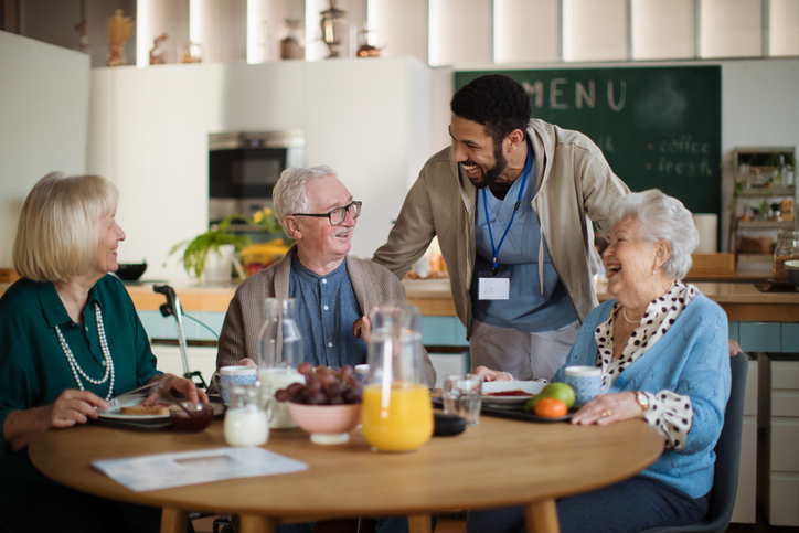 Staff member talking with seniors during a meal at Brookwood Point