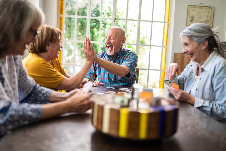 Senior man and woman high-fiving while playing a game with friends