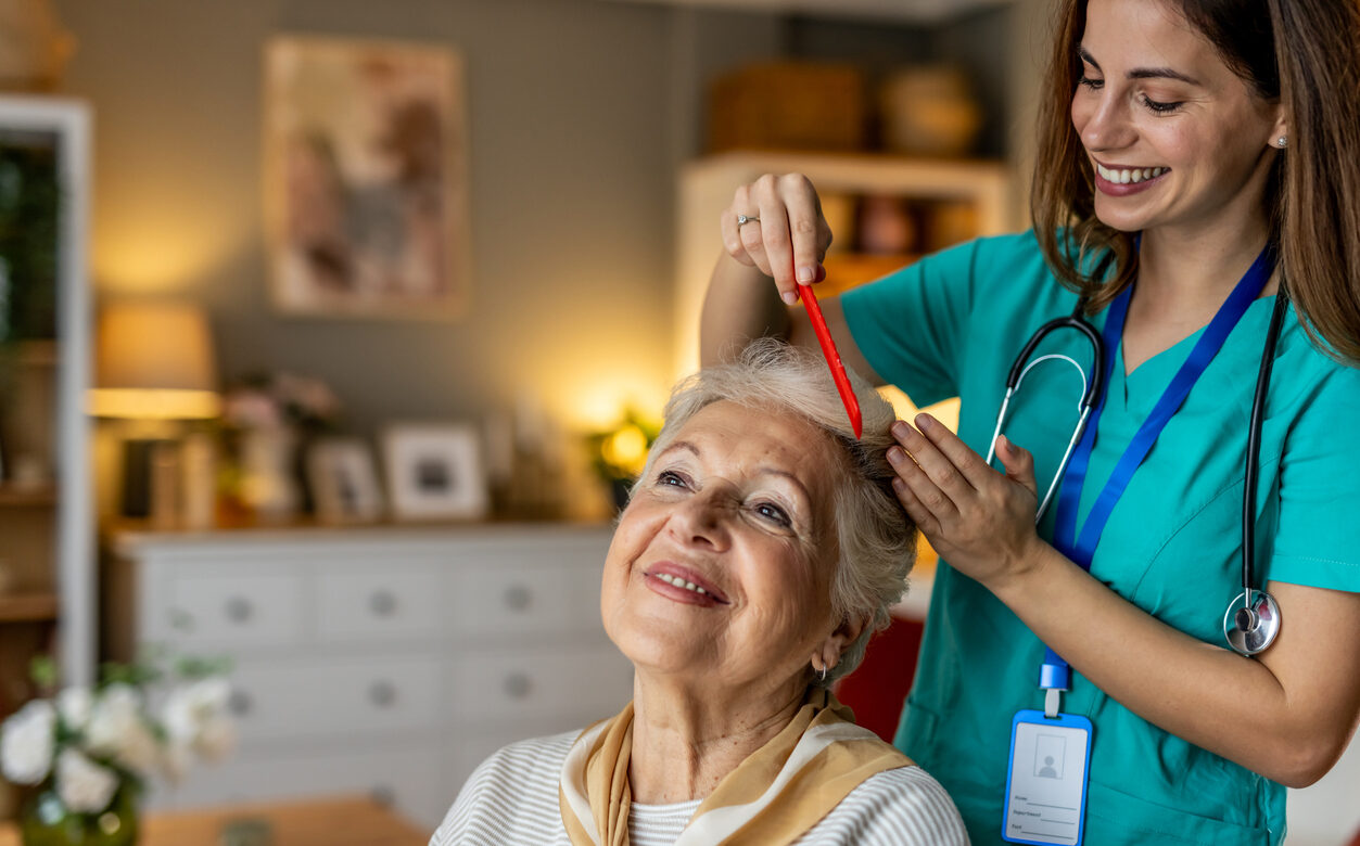 Caregiver combing a senior woman's hair in a bright room