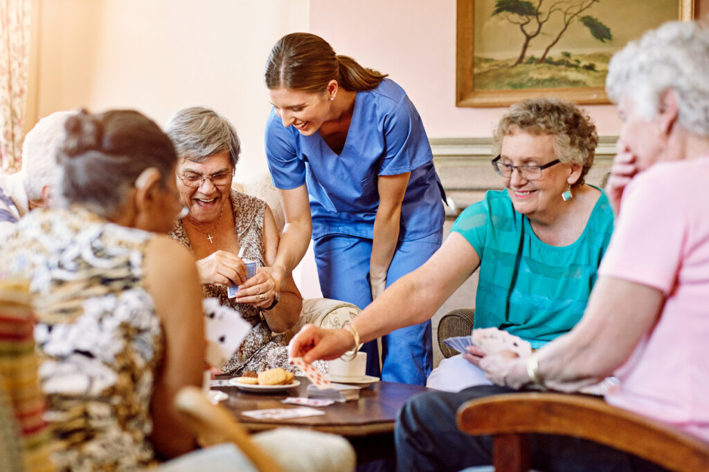 Senior woman smiling at a nurse holding a vase of tulips