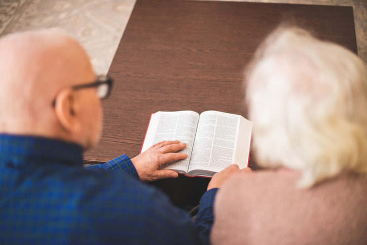 Senior couple reading a Bible or book together at a wooden table
