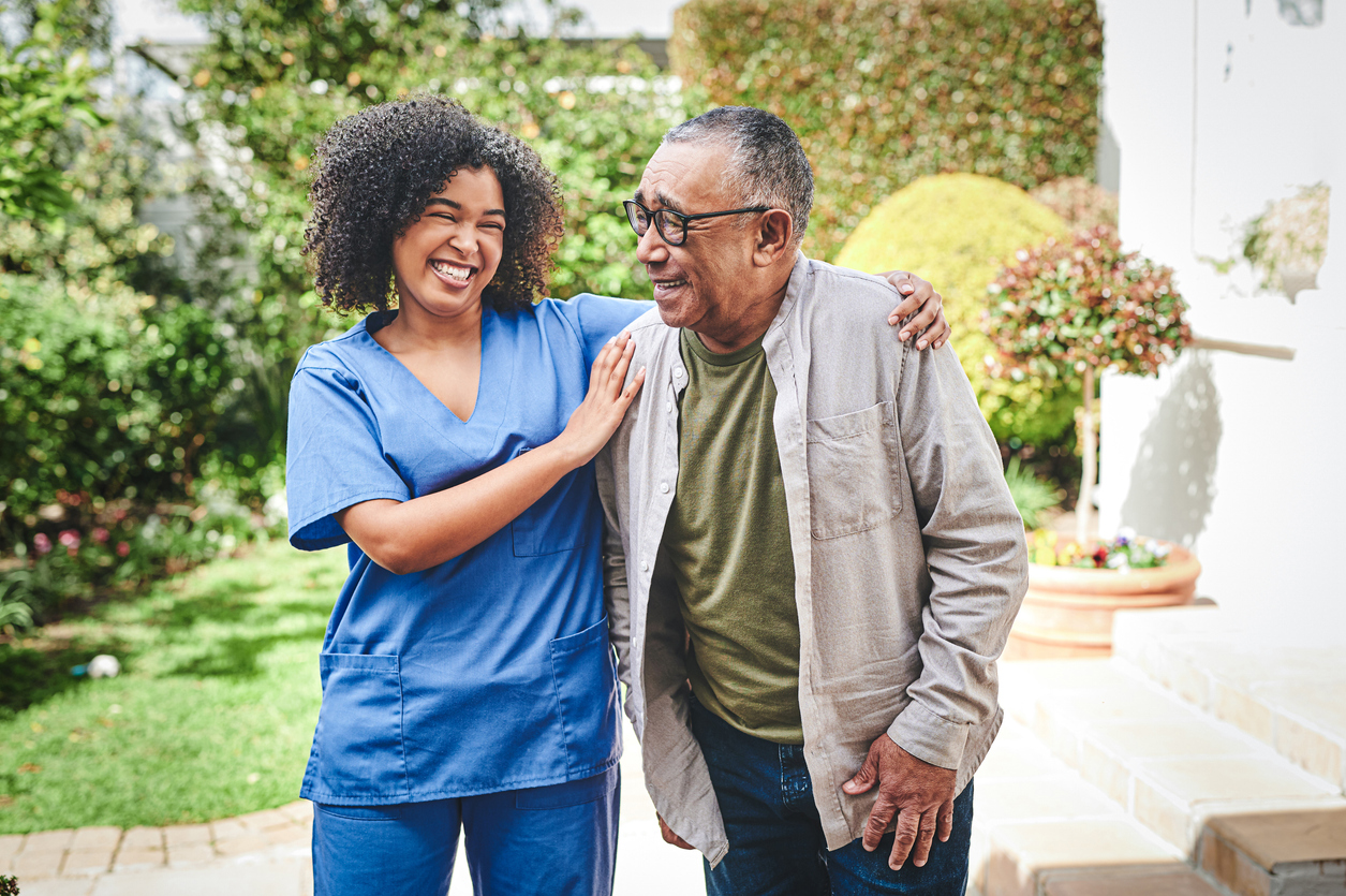 Caregiver and senior man smiling outdoors