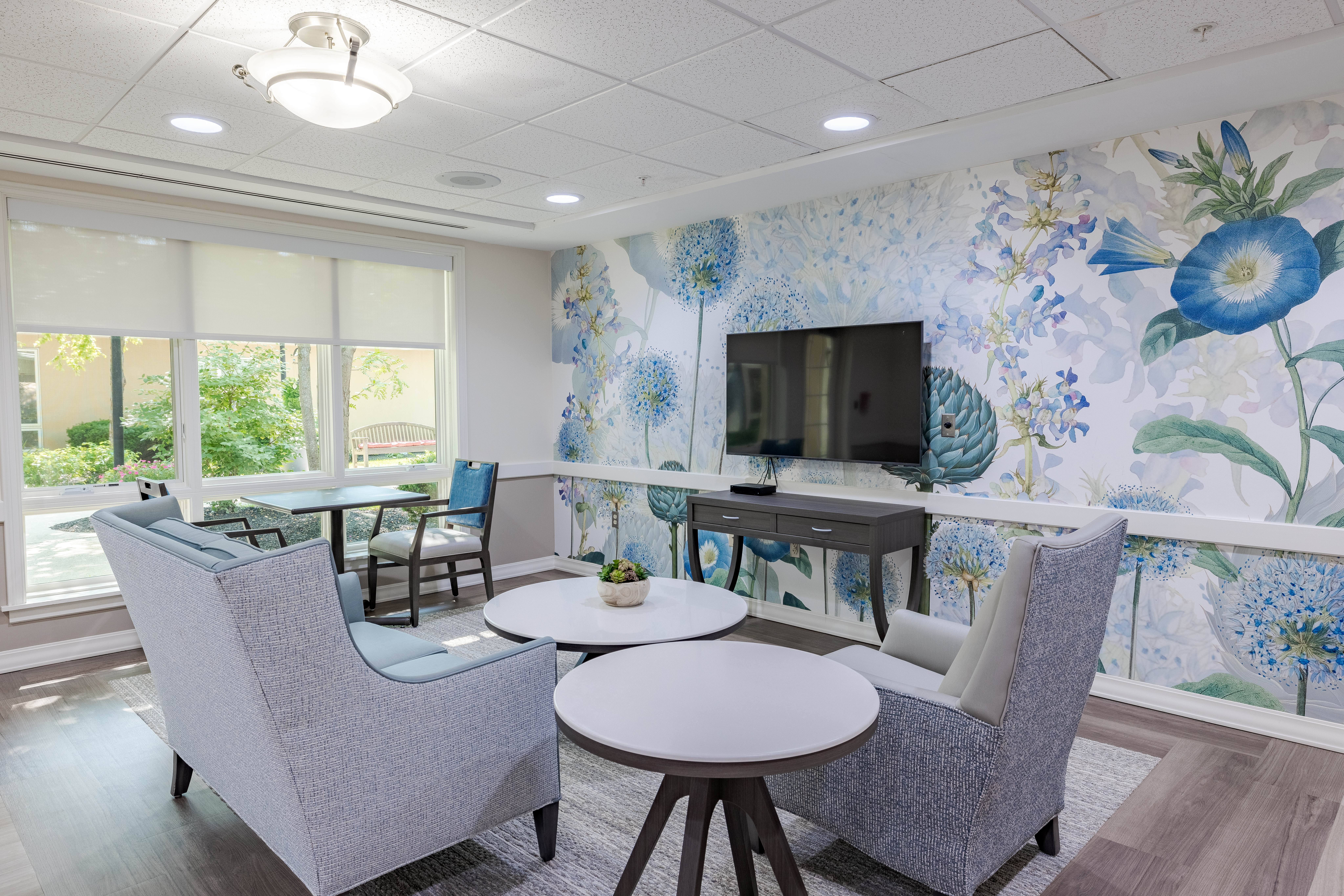 Lounge area with floral wallpaper, a TV, and comfortable seating