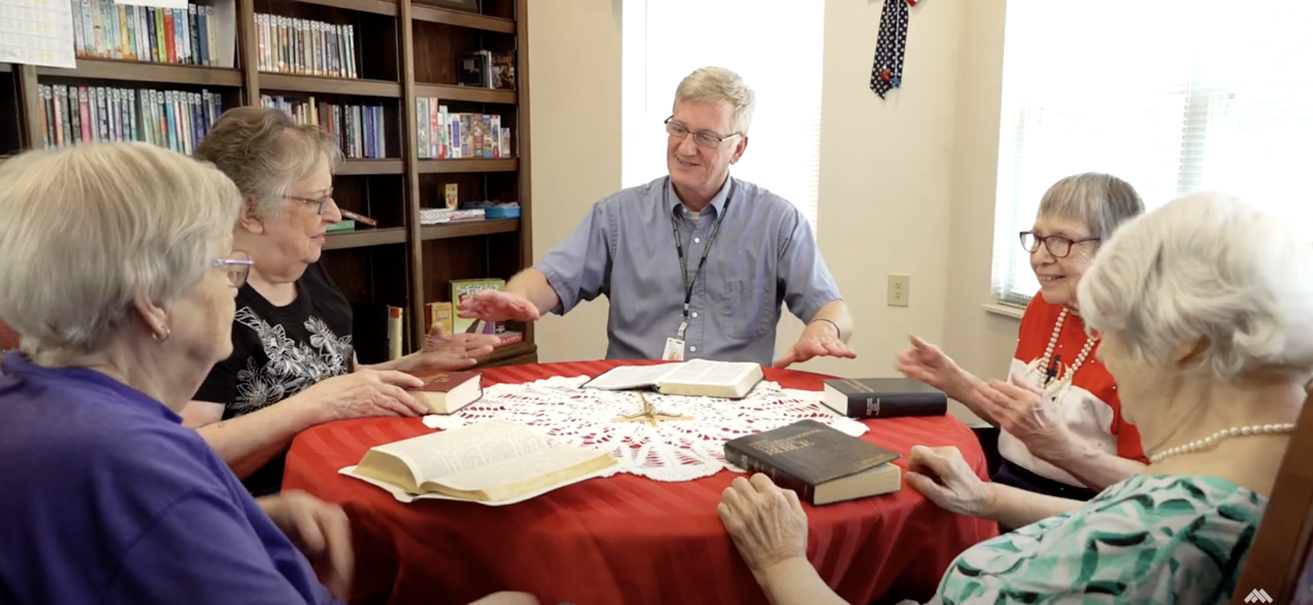 Chaplain with residents, holding hands around the table