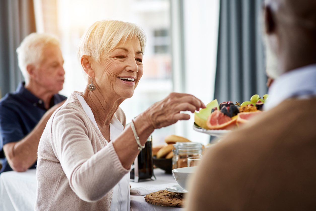 Group of seniors laughing and talking at a dining table