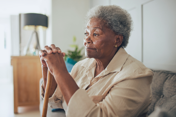 senior woman sitting down with a cane in her hand