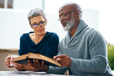 Two seniors looking through a book together