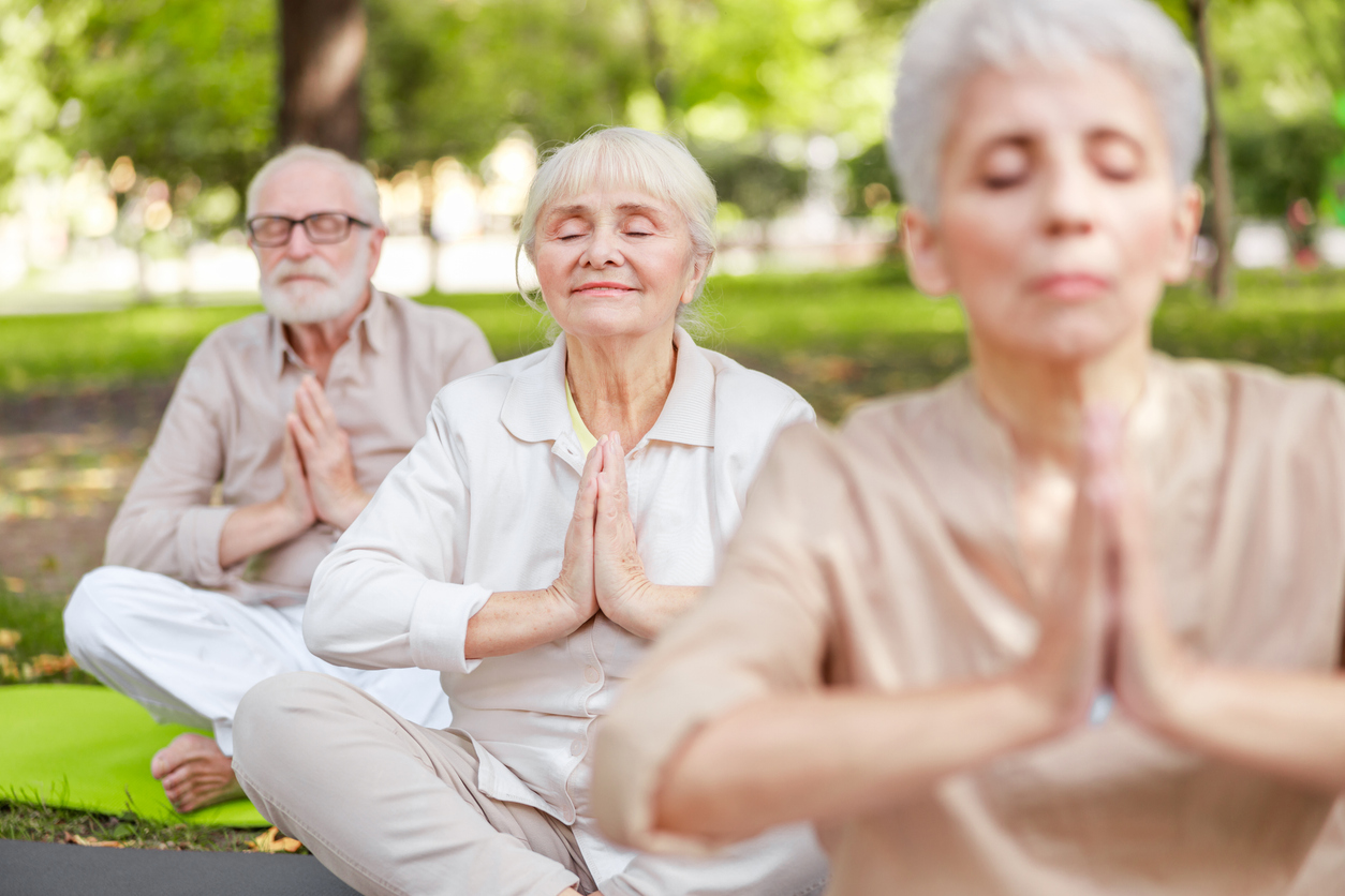 Seniors meditating in an outdoor yoga class