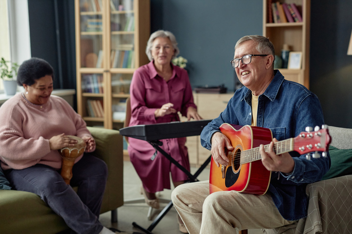 Seniors playing music together with a guitar keyboard and hand drum