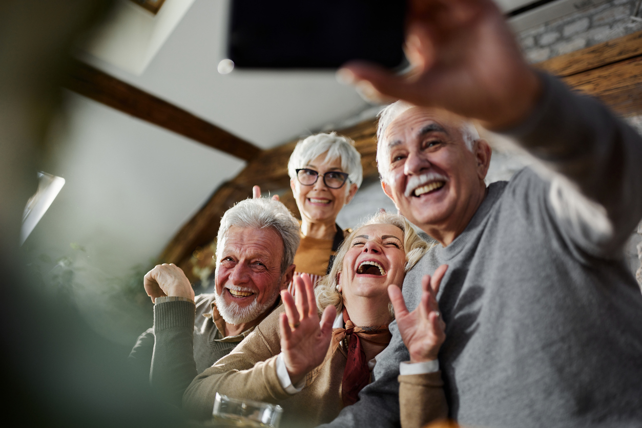 Seniors laughing while talking on a smartphone outdoors
