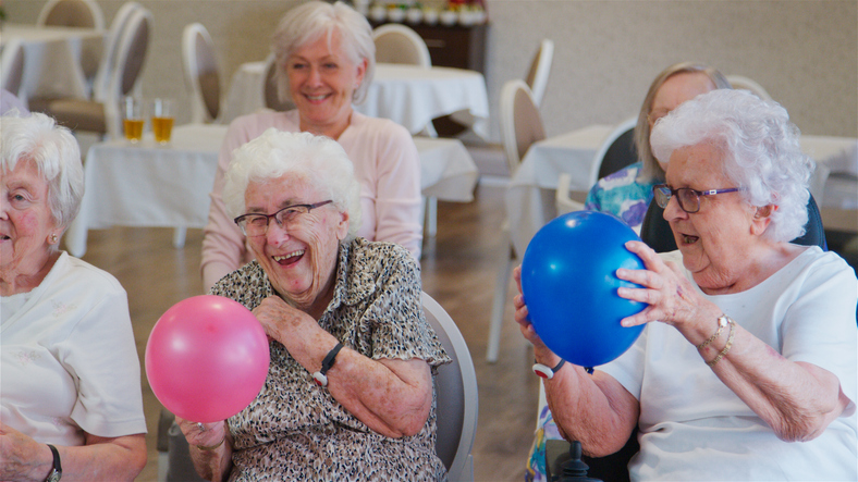 Seniors playing with balloons during a wellness activity at Brookwood Point