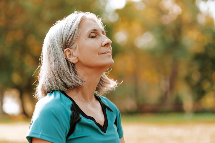 Senior woman meditating outdoors in nature