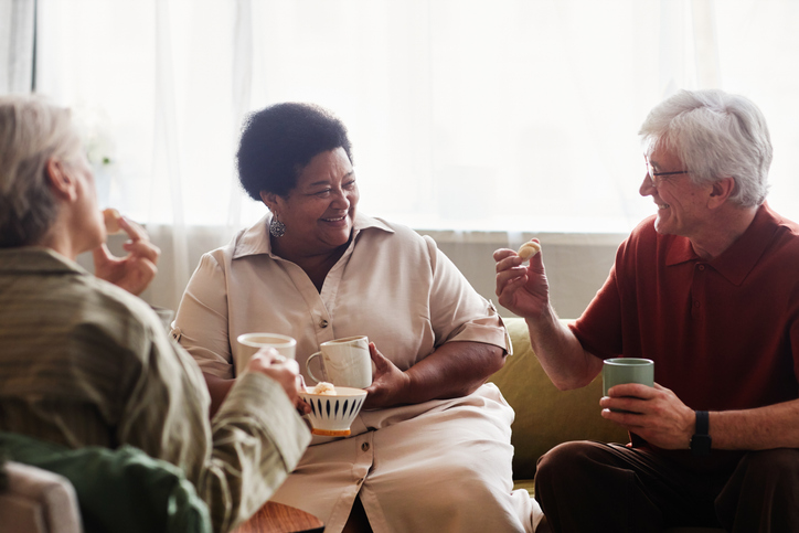 Group of seniors enjoying tea time together and chatting at home.